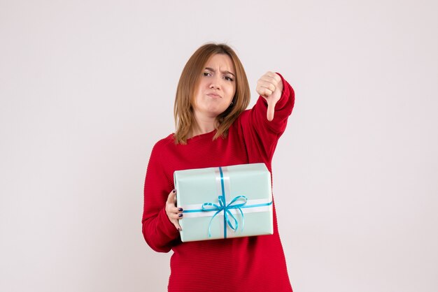 Вид спереди молодая женщина, стоящая с подарком на рождество
