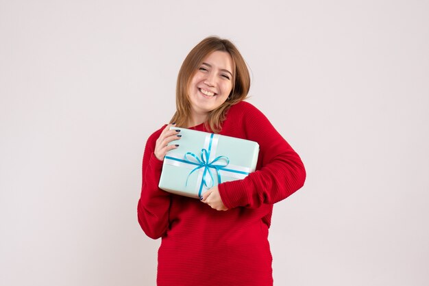 Вид спереди молодая женщина, стоящая с подарком на рождество