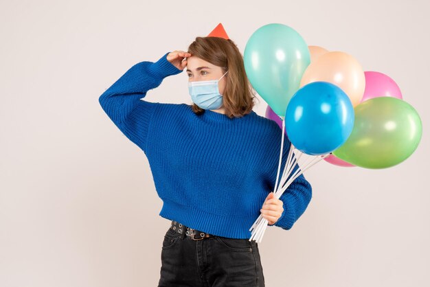 Front view young female in sterile mask holding colorful balloons