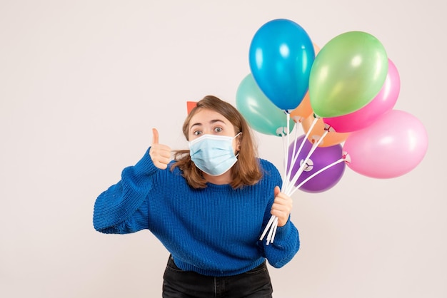 Front view young female in sterile mask holding colorful balloons