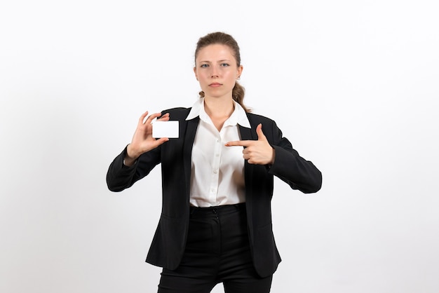 Front view young female in strict classic suit holding white card on white desk job business female work costume woman