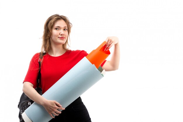 A front view young female student in red shirt black bag smiling holding big file on the white