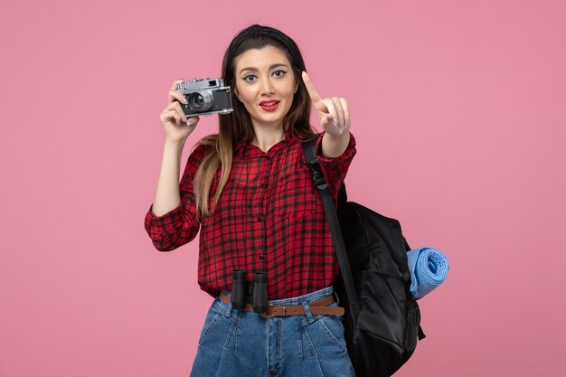 ピンクの背景写真の女性の色でカメラで写真を撮る正面図若い女性