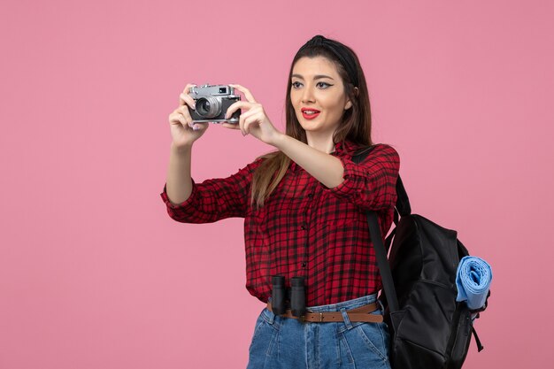 Вид спереди молодая женщина фотографирует с камерой на розовом фоне цвет фото женщины