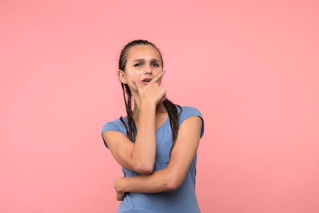 Front view of young female thinking on pink