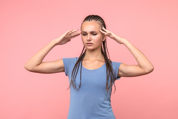 Front view of young female thinking on pink