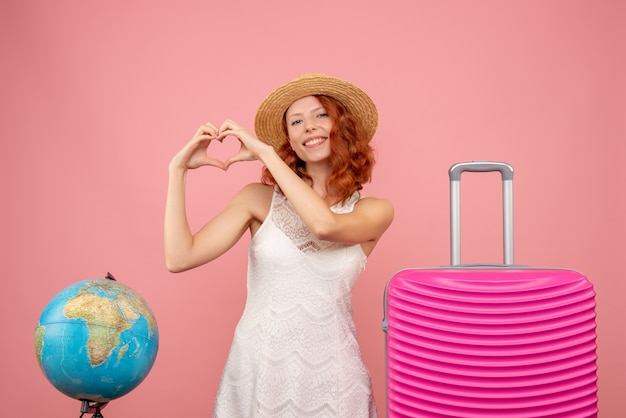 Front view of young female tourist with pink bag on light-pink wall