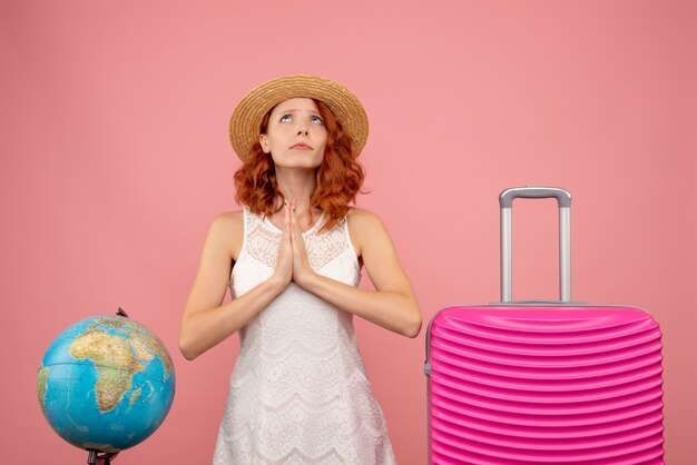 Front view of young female tourist with pink bag on light wall