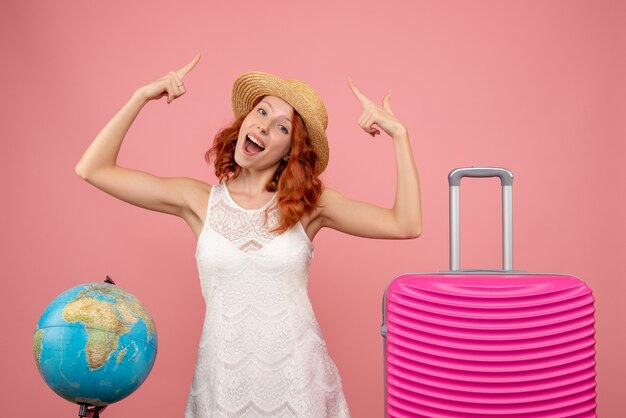 Front view of young female tourist with pink bag on pink wall