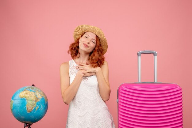 Front view of young female tourist with pink bag on pink wall