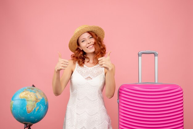 Front view of young female tourist with pink bag on pink wall