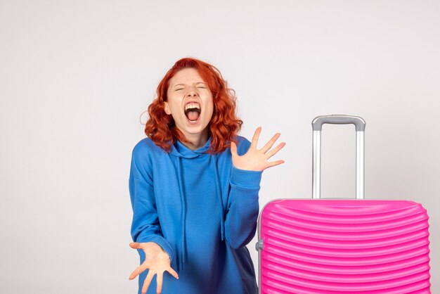 Front view of young female tourist with pink bag on white wall