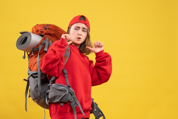 Front view young female traveler with backpack pointing at herself