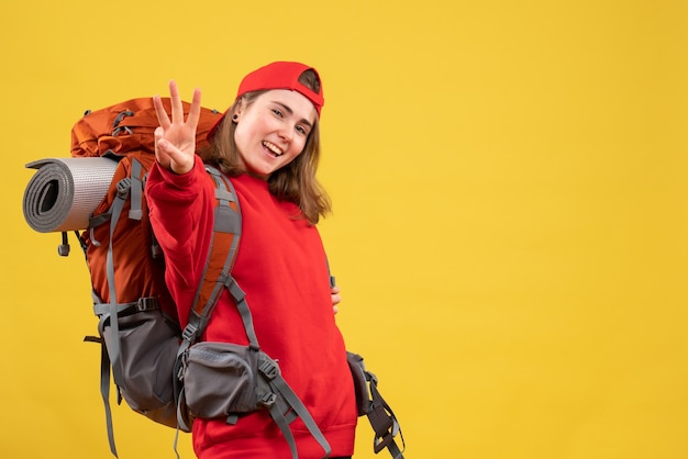 Front view young female traveler with backpack showing three fingers