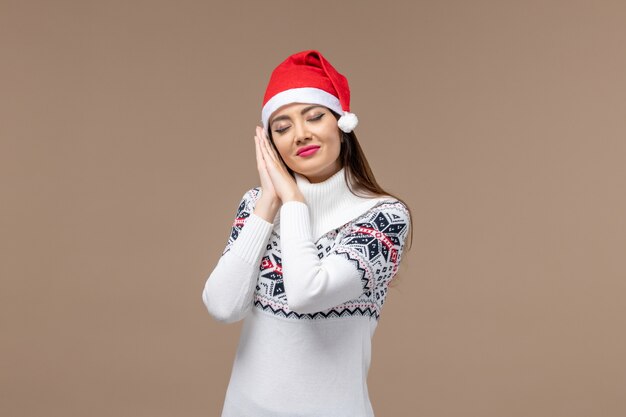 Front view young female trying to sleep in red cap on brown background emotion christmas new year