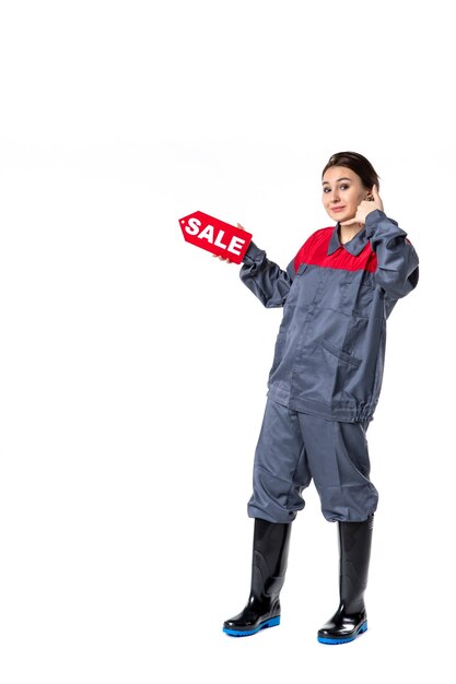 front view young female in uniform holding sale nameplate on white background