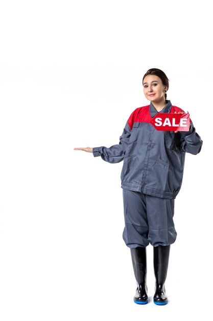 front view young female in uniform holding sale written nameplate on white background