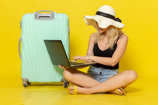 Front view young female using laptop on yellow wall girl voyage trip vacation journey sun