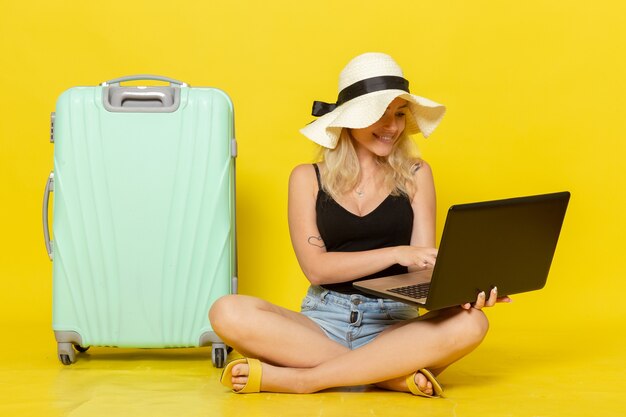 노란색 벽 소녀 항해 휴가 여행 여행 태양에 노트북을 사용하는 전면보기 젊은 여성