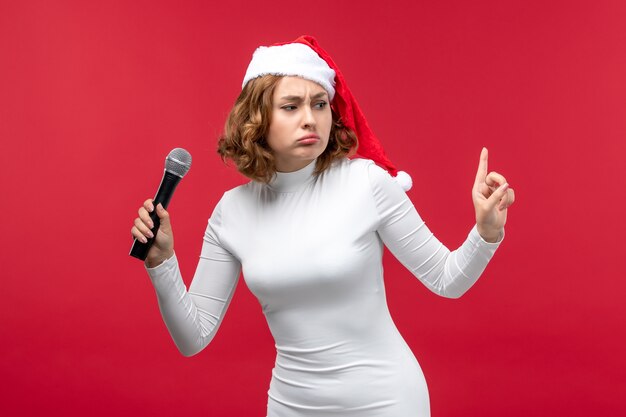Вид спереди молодой женщины, использующей микрофон на красном
