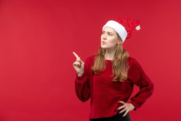Вид спереди молодая женщина в рождественской шляпе санта-клауса на красном столе праздничная красная женщина