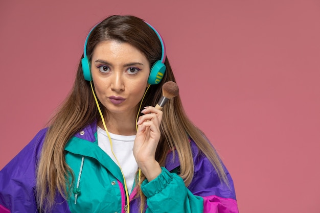 Front view young female in white shirt colorful coat holding brush for make-up