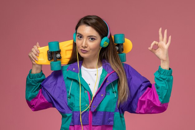 Front view young female in white shirt colorful coat holding skateboard