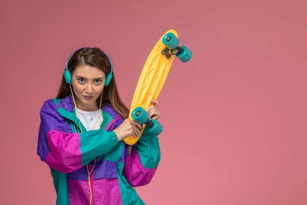 Front view young female in white shirt colorful coat holding skateboard