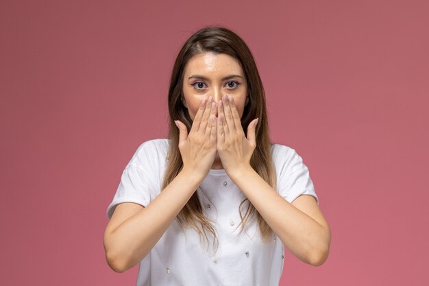 Front view young female in white shirt covering her mouth