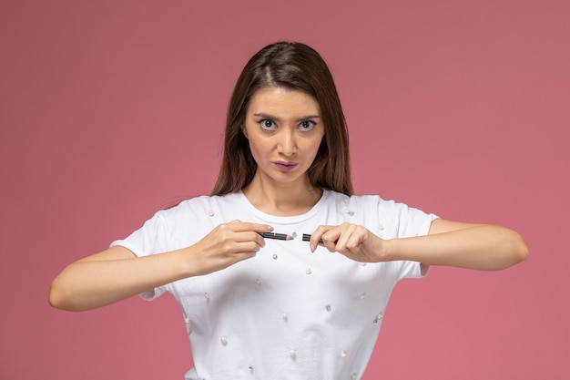 Front view young female in white shirt posing on pink wall, color woman model posing woman