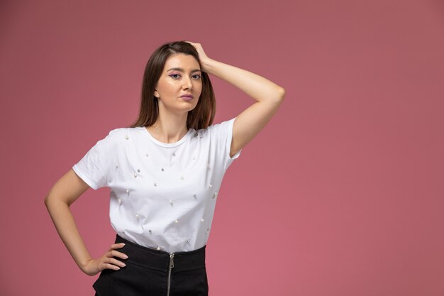 Front view young female in white shirt simply posing on pink wall, color woman model woman