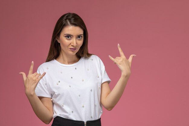 Front view young female in white shirt smiling rocker posing on the pink wall