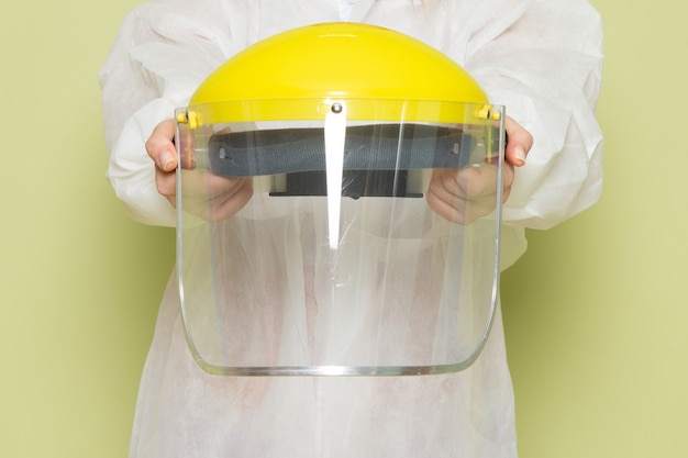 Free photo front view young female in white special suit and yellow helmet holding special protective helmet on the green space