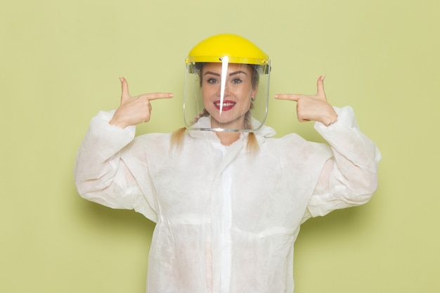흰색 특수 양복과 녹색 공간 작업에 웃 고 노란색 헬멧에 전면보기 젊은 여성