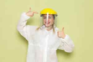 Free photo front view young female in white special suit and yellow helmet smiling on the green space job