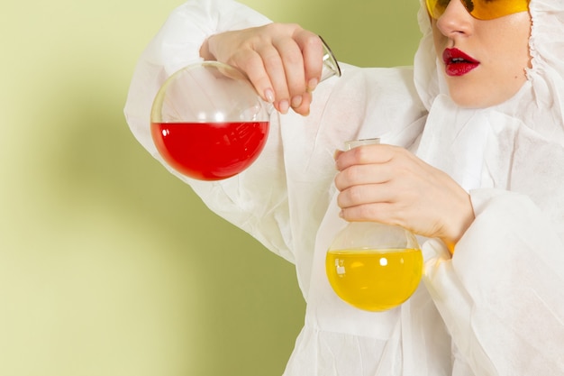 Foto gratuita giovane donna di vista frontale in vestito speciale bianco e casco giallo che lavora con le soluzioni sul lavoro dello spazio verde