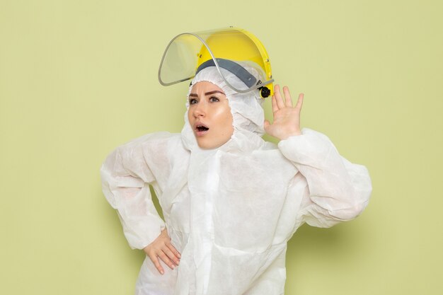 白の特別なスーツと緑の宇宙服の制服の科学について聞いてみようと黄色の保護用のヘルメットの正面の若い女性