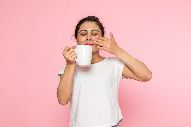 A front view young female in white t-shirt and blue jeans drinking tea