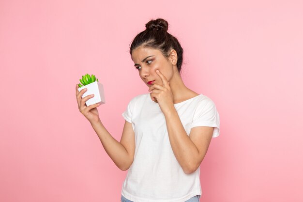 A front view young female in white t-shirt and blue jeans holding plant