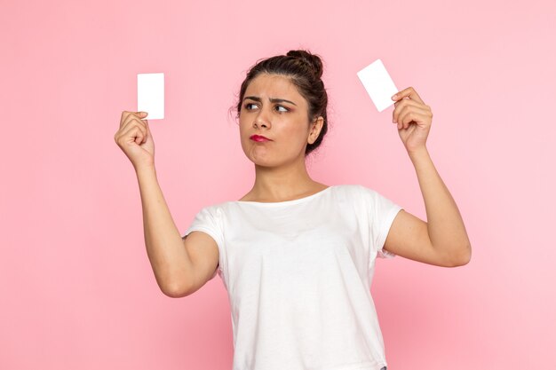 A front view young female in white t-shirt and blue jeans holding white cards