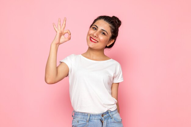 A front view young female in white t-shirt and blue jeans posing with happy expression