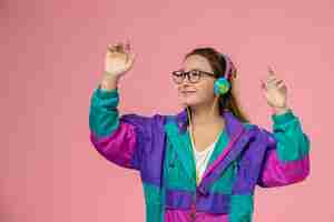 Free photo front view young female in white t-shirt ed coat listening to music via earphones on the pink background