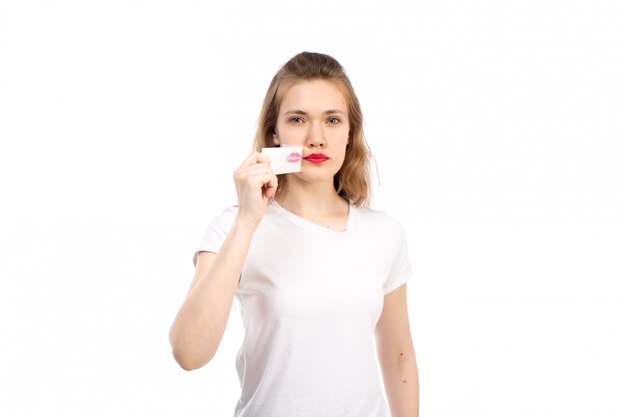 A front view young female in white t-shirt with white bandage around her mouth taking it off on the white