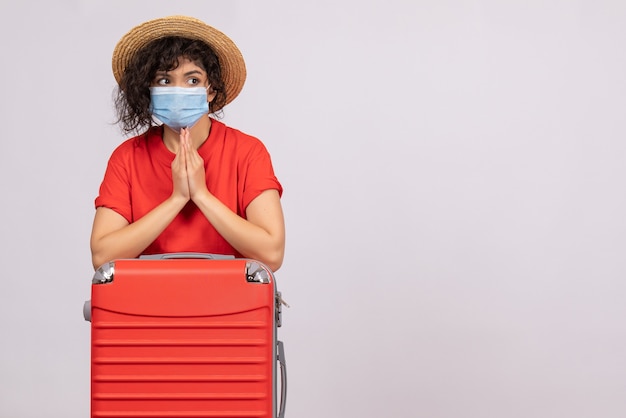 Vista frontale giovane donna con borsa in maschera su sfondo bianco colore covid- virus del sole pandemico viaggio vacanza turistica