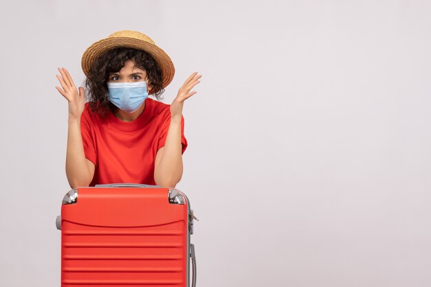 Вид спереди молодая женщина с сумкой в маске на белом фоне цвета covid- пандемический отпуск поездка солнечный туристический вирус