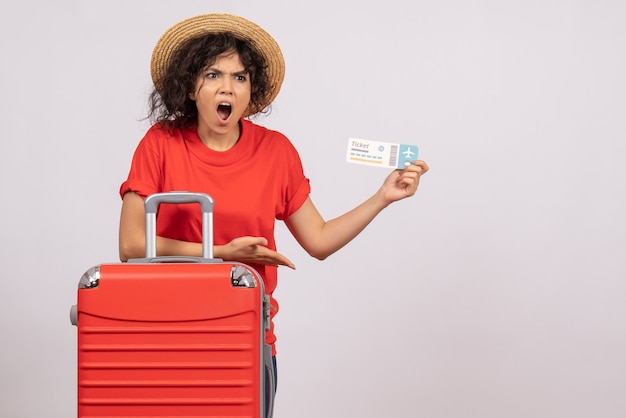 Вид спереди молодая женщина с сумкой, готовящаяся к поездке, держа билет на белом фоне, самолет путешествия солнца туристический отпуск цветной полет