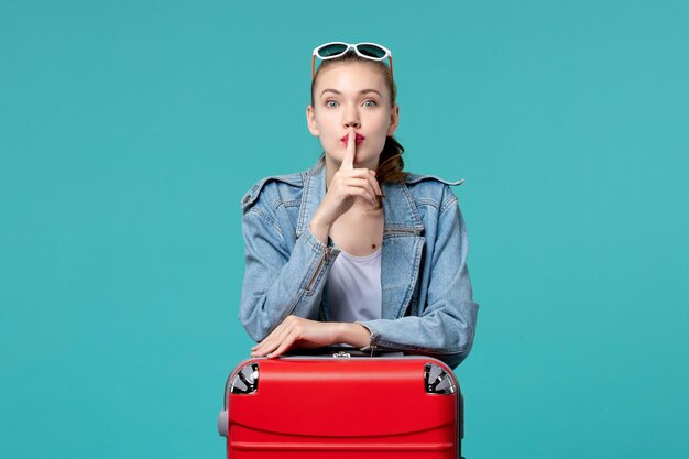 Giovane femmina di vista frontale con la borsa che prepara per la vacanza e che chiede di tacere sullo spazio blu