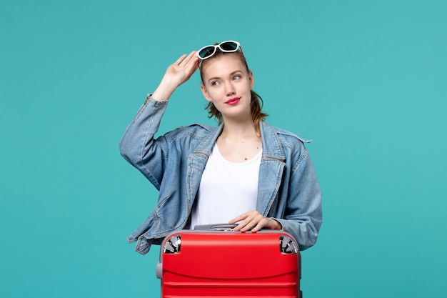 青い机の上で休暇の準備をしているバッグを持つ若い女性の正面図