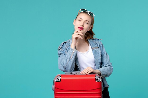 休暇の準備と青い空間を考えてバッグを持つ若い女性の正面図