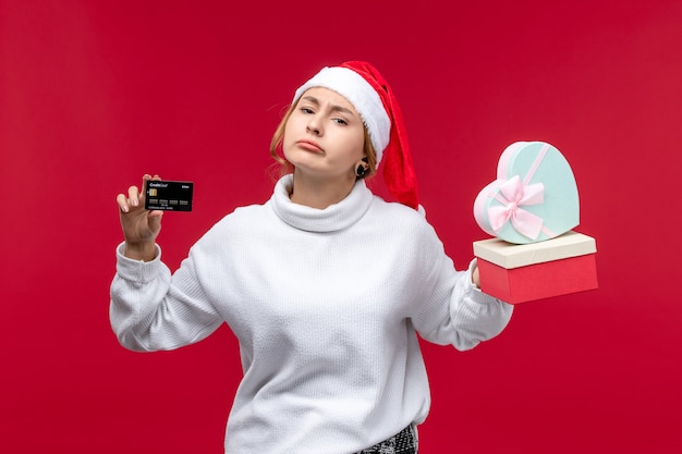 Front view young female with bank card and gifts on a red background